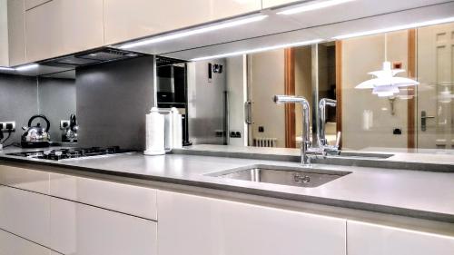 cocina blanca con fregadero y fogones en BizFlats Eixample Apartments, en Barcelona