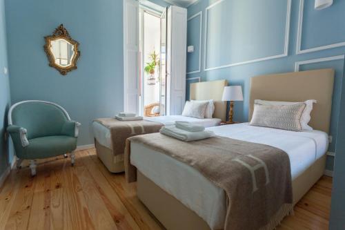 a blue bedroom with two beds and a chair at Oporto City View - Santo Ildefonso Lovely in Porto