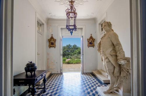 a statue of a woman in a hallway with a chandelier at Quinta do Tojal in Ferreira do Zêzere