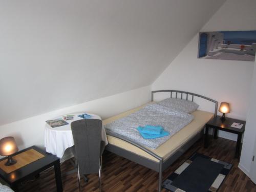 Dormitorio pequeño con cama y mesa en Gästehaus Am Linus en Lingen