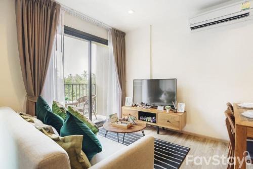 a living room with a couch and a tv at Rain Cha-am Huahin By Sake in Cha Am