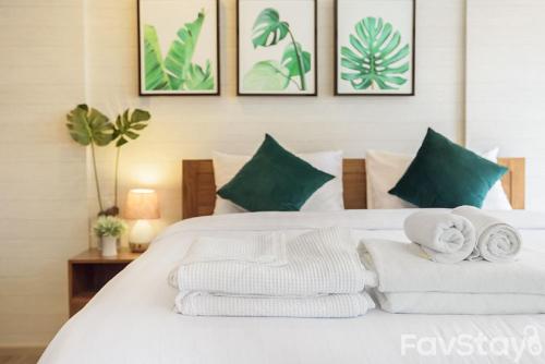 a bedroom with a white bed with towels on it at Rain Cha-am Huahin By Sake in Cha Am