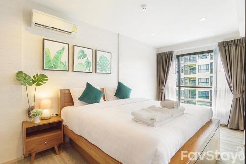 a bedroom with a large white bed and a window at Rain Cha-am Huahin By Sake in Cha Am
