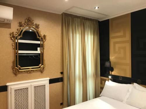 Schlafzimmer mit einem Bett und einem Wandspiegel in der Unterkunft Magis Ac Magis Bedrooms Versilia in Viareggio