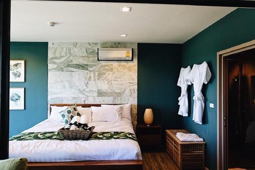 a bedroom with green walls and a bed with a basket on it at Rain Cha-am Huahin By Sake in Cha Am
