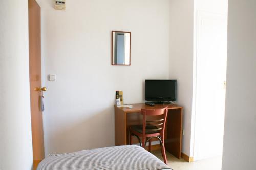 a bedroom with a desk with a computer and a bed at Hostal Plaja i Pati de Can Plaja in Palafrugell