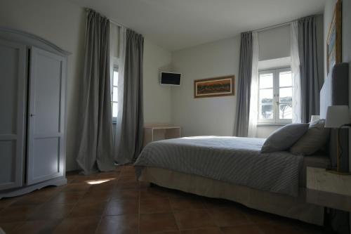 a bedroom with a bed and two windows at Locanda La Bottega del Parco in Pisa