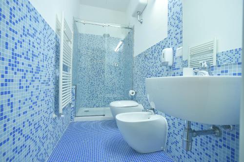 a blue tiled bathroom with a toilet and a sink at Locanda La Bottega del Parco in Pisa