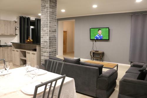 a living room with a couch and a tv on a wall at Chalet Pkhelshe in Kazbegi