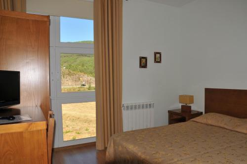 a bedroom with a bed and a large window at Casa Lagar Da Alagoa in Manteigas