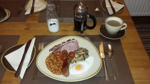 a white plate topped with breakfast foods and a cup of coffee at Meadowlea Guest House in Okehampton