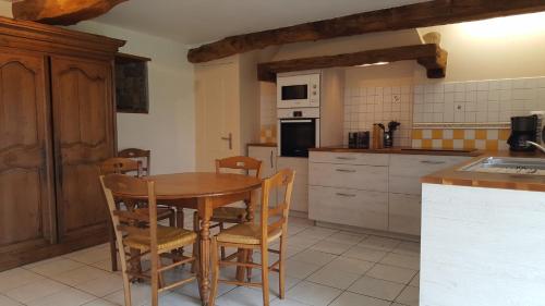 a kitchen with a wooden table and chairs at Le BOCAGE in Sartilly