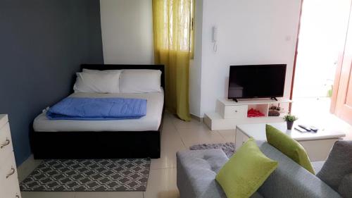 een slaapkamer met een bed, een bank en een tv bij Cheb's House in Abidjan