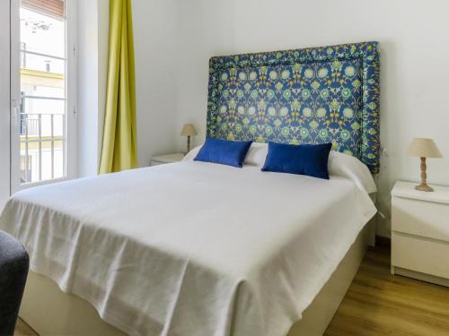a bedroom with a large white bed with blue pillows at Living-Sevilla Feria in Seville