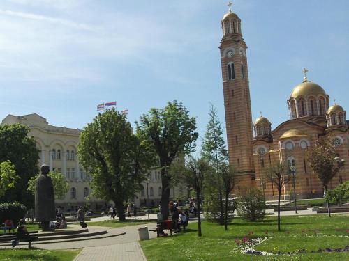a large building with a clock tower in a park at Stan na dan Banja Luka in Banja Luka