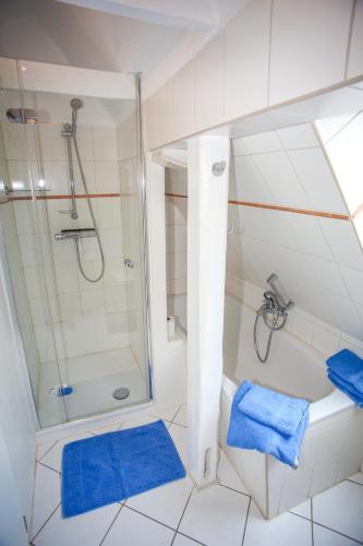 a bathroom with a shower and a bath tub with blue towels at Ferienwohnung Wieben in Sankt Peter-Ording