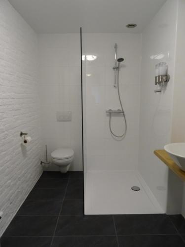 uma casa de banho branca com um chuveiro e um WC. em Aan 't kapelke em Valkenburg