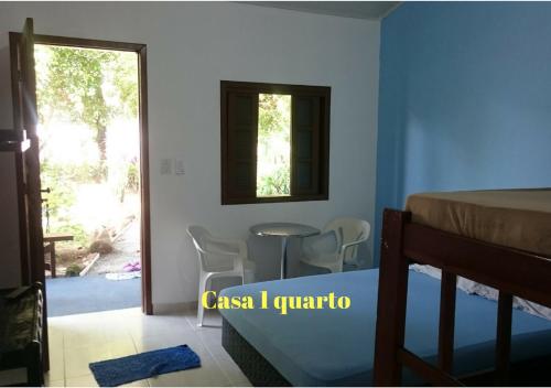 a bedroom with a bed and a table and a window at Estacao Paraiso Chalé in Bertioga
