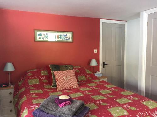 a red bedroom with a bed with a hat on it at Westwaterhead in Kingsbridge