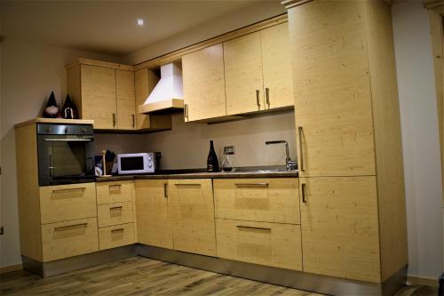 eine Küche mit Holzschränken und einer Mikrowelle in der Unterkunft Enrosadira in Molveno