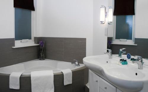 a bathroom with two sinks and a tub with towels at Queens Hotel & Spa in Brighton & Hove
