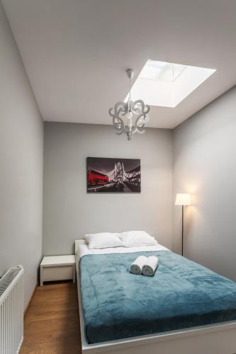 a white bedroom with a bed and a chandelier at Apartamenty Centrum Częstochowa Stara Kamienica in Częstochowa