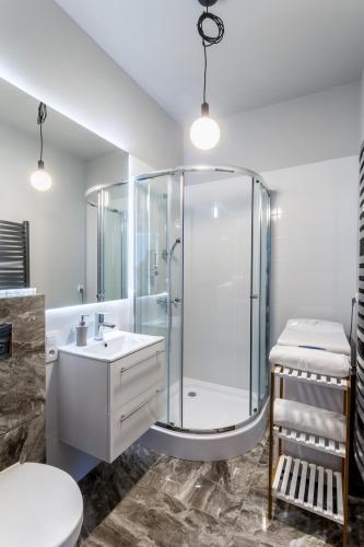 a bathroom with a glass shower and a sink at Apartamenty Centrum Częstochowa Stara Kamienica in Częstochowa