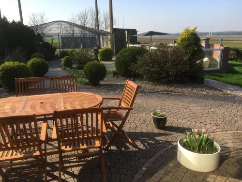 a wooden table and chairs on a brick patio at B&B De Kaagse Koe in Huigsloot