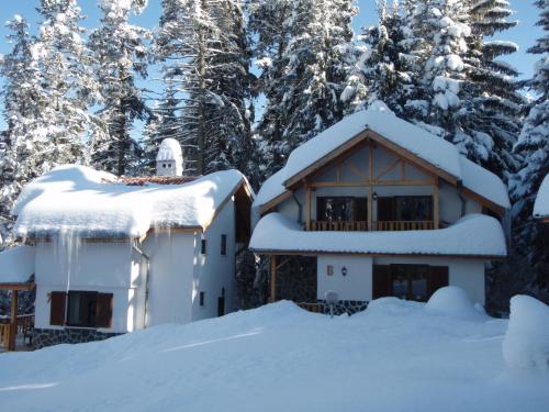 a house covered in snow with trees in the background at Saint George Holiday Village in Borovets