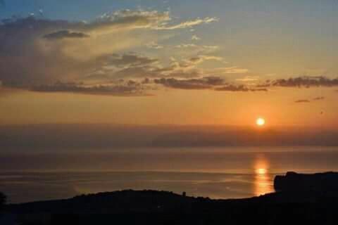a sunset with the sun in the sky at B&B Tre Giummare in Scopello