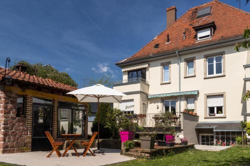a house with an umbrella and a table and chairs at Carpe Diem Bed & Breakfast in Sélestat