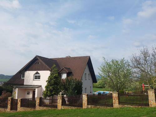 a white house with a brown roof behind a fence at Vila na Skalce in Česká Kamenice