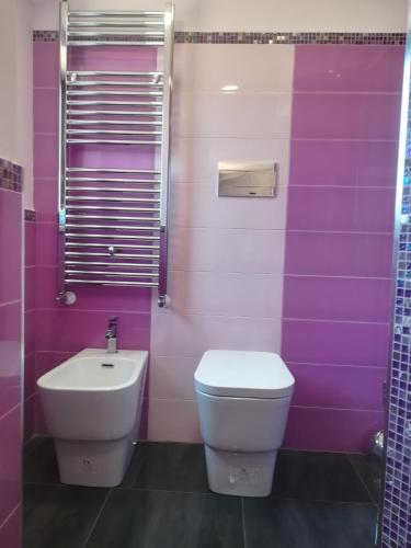 a purple bathroom with a toilet and a sink at Attico Sole Luna in Taormina