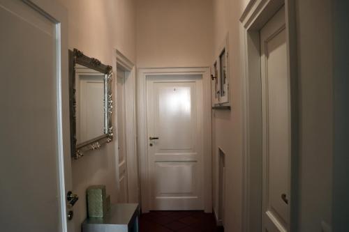 um corredor com uma porta branca e um espelho em Paradiso24 em Forlì