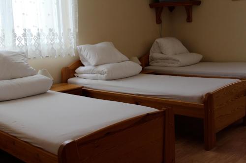three twin beds in a room with a window at Penzion Lucs in Heľpa