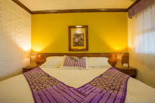 a bedroom with a large bed in a yellow wall at Hotel y Centro de Convenciones Jardines del Lago in Panajachel