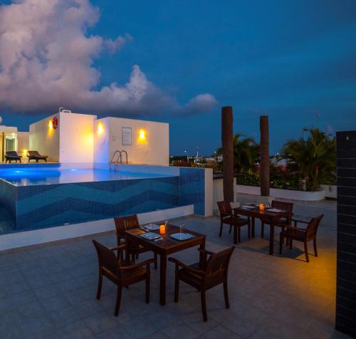 a patio with tables and chairs next to a swimming pool at Angelo's Hotel in Playa del Carmen