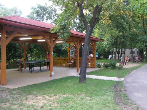 a wooden pavilion with a picnic table in a park at Árnyas Thermal Camping és Üdülőpark in Püspökladány