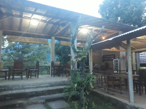 a wooden pergola with tables and chairs on a patio at Sugi Gede Homestay in Singaraja