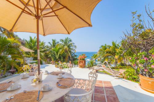 a table with an umbrella and the ocean in the background at Villas Fasol Huatulco in Santa Cruz Huatulco