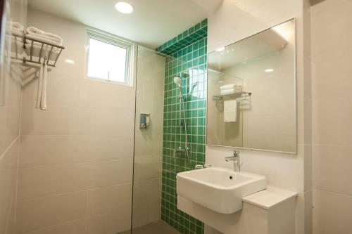 a bathroom with a sink and a glass shower at Aman Hills Hotel in Kampong Timbunan