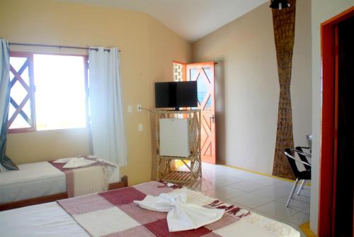 a bedroom with a bed and a tv and a window at Chalemar Hotel Pousada in Baía Formosa