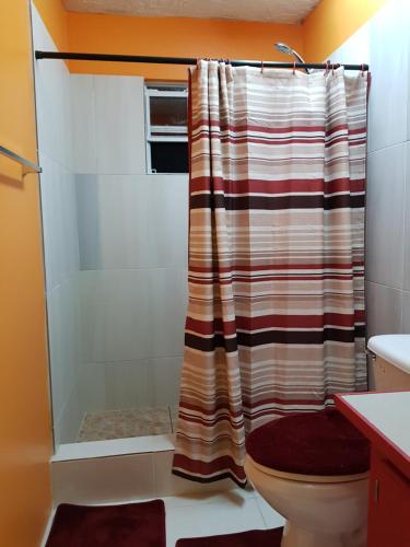 a bathroom with a shower curtain and a toilet at Tequila Sunrise Antigua in Osbourn