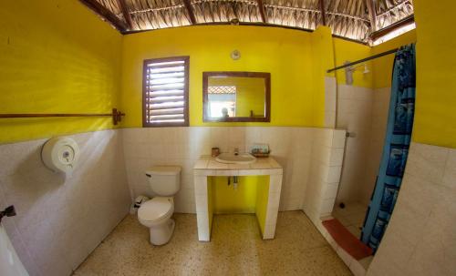 a yellow bathroom with a toilet and a sink at Hotel Cafe del Sol in Monterrico