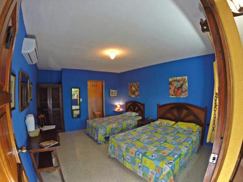 a bedroom with two beds and blue walls at Hotel Cafe del Sol in Monterrico