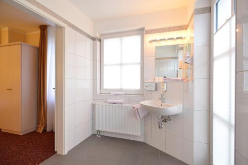 a white bathroom with a sink and a window at Hotel Behrmann in Hamburg