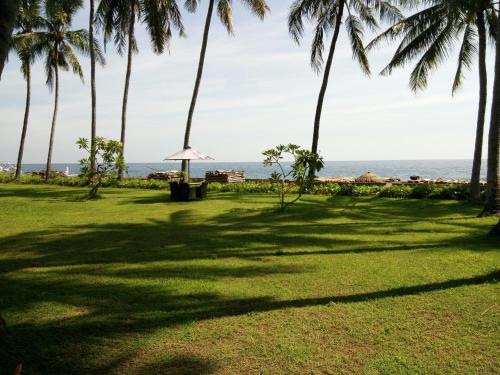 a park with palm trees and the ocean at The Amrita - Salt Farm Villas in Tejakula