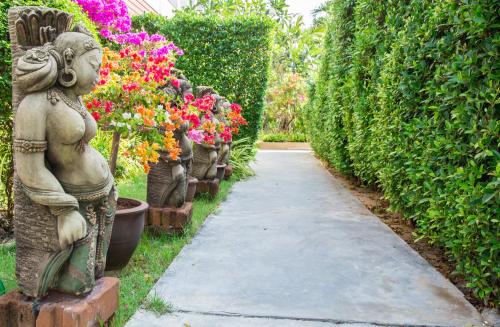 a path in a garden with statues and flowers at Lamai Coconut Beach Resort in Lamai