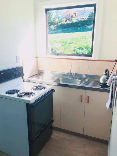 a kitchen with a stove and a sink and a window at Greenacres Alpine Chalets & Villas in Hanmer Springs