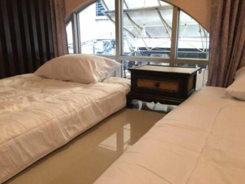 twee bedden in een kamer met een tafel en een raam bij The Grand Palace Hostel in Bangkok